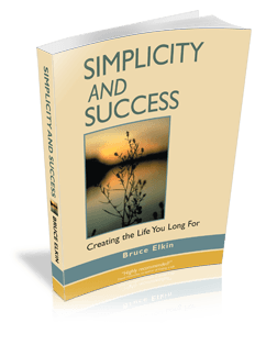 A 3-D photo of the book Simplicity and Success, by Bruce Elkin. It is standing on a table, throwing a shadow. As well as the title, there is a photo of a peace pond at sunset.